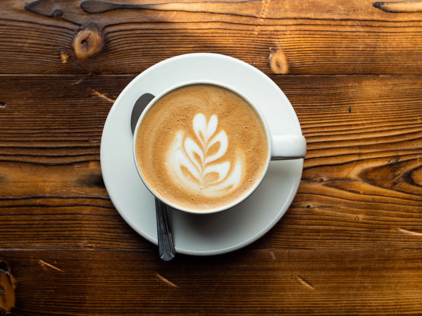 Latte with rosetta art seen from above on a wooden table