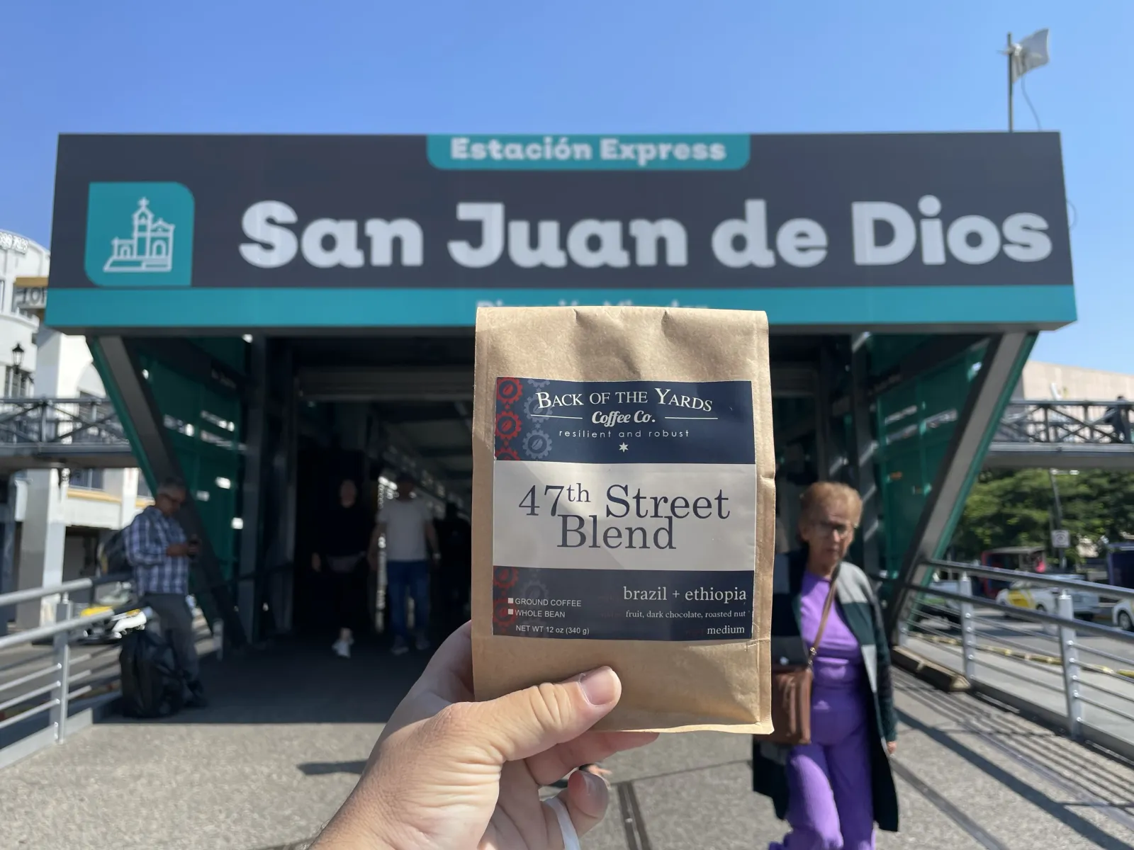 A bag of Back of the Yards coffee held up at the San Juan de Dios market entrance
